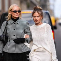 Guest wears sunglasses , a black turtleneck, a black and white oversized houndstooth pattern printed jacket with puff sleeves ; a guest wears a...