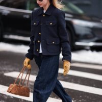 Guest wears sunglasses, a blue military jacket with golden buttons, blue flared denim pants / jeans , orange gloves, a brown bag, outside Ulla...