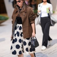 Guest wears sunglasses, a gray jacket, a black top, a black and white polka dots mini skirt , sandals, outside Toteme, during New York Fashion Week,...