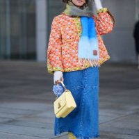 Guest wears sunglasses, a khaki / gray / blue wool fringed scarf, an orange floral print padded jacket with yellow lines, a pastel pale Vuitton bag,...