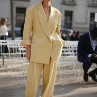 Guest wears sunglasses, a pale pastel yellow oversized blazer jacket, matching flared pants, before Stella McCartney, during the Womenswear...