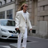 Guest wears sunglasses,, a white lustrous silk oversized blazer jacket, a white top from Courreges, white pants, pointed shoes, outside Alessandra...