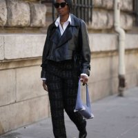 Guest wears sunglasses, a white shirt, a black leather jacket, black pants, a mauve bag, leather shiny shoes, outside Hermes, during the Womenswear...
