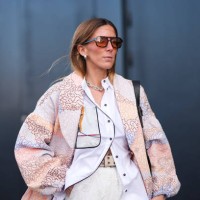 Guest wears sunglasses, a white shirt, a pastel pale floral print flowing oversized light jacket , a beige studded belt, outside Munthe, during the...