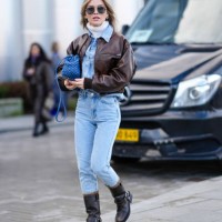 Guest wears sunglasses, a white turtleneck pullover, a blue denim shirt, a blue woven leather bag, blue denim jeans pants , brown leather boots...