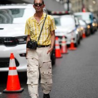 Guest wears sunglasses, a yellow and white checkered shirt, a camera in a leather camera bag, a Telfar belt, beige trousers, black leather shoes,...