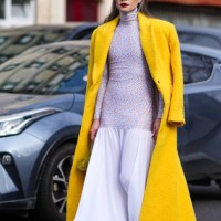 Guest wears sunglasses, red lipstick, a yellow fluffy long wool coat , a floral print turtleneck top / long dress with gathered bottom part, outside...