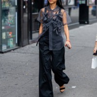 Guest wears transparent grey top, black pants outside Puppets and Puppets on September 13, 2023 in New York City.