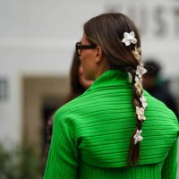 Guest wears white and black flower hair clips, brown marble print pattern sunglasses, a neon green embossed striped pattern top, outside Baum und...