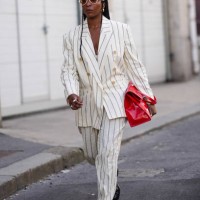 Guest wears white glasses, earrings, rings, an oversized double-breasted white jacket with thin black stripes, matching large pants, black leather...