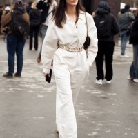 Guest wears white one piece with big chain belt and black Chanel bag outside the Chanel fashion show during the Womenswear Fall/Winter 2025/2026 as...