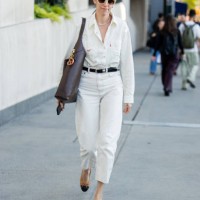 Guest wears white pants, shirt, brown bag outside Michael Kors during New York Fashion Week on September 10, 2024 in New York City.