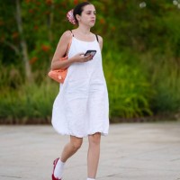 Guest wears white red scrunchie, bright pastel orange bag, white midi dress,white socks, dark red heeled ballerina leather shoes, outside Marimekko,...
