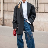 Guest wears white shirt, black blazer, decorated jeans, red heels and bag, red Nike beret, outside Miu Miu, during the Womenswear Fall/Winter...