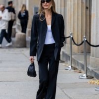 Guest wears white shirt, black blazer, striped pants, sunglasses, sandals outside Horror Vacui during the Berlin Fashion Week SS25 on July 03, 2024...