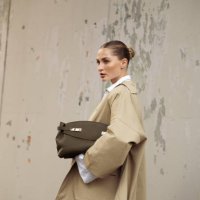 Guest wears white shirt, white skirt, beige coat and olive green bag outside Ferragamo show during the Milan Fashion Week Spring/Summer 2025 on...