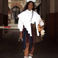 Guest wears white shirt, white socks, sneakers, pleated colourful skirt and brown bag outside Stem presentation during the Copenhagen Fashion Week...