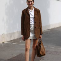 Guest wears white t-shirt, silver mini skirt, brown suade blazer, black loafers, brown tote bag, outside Ferragamo, during the Milan Fashion Week...