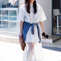 Guest wears white t-shirt, white sheer midi skirt, denim shirt on the waist, green sandals, brown pouch bag, outside Kartik Research, during the...