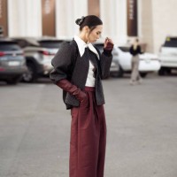 Guest wears wide burgundy pants, white shirt, burgundy leather gloves, grey cropped coat during the 10th season of the Visa Fashion Week Almaty on...