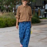 Guest wears yellow houndstooth button shirt, denim jeans with print, yellow bag outside Marimekko during day four of the Copenhagen Fashion Week SS25...