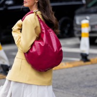 Guest wears yellow jacket, red bag, white skirt outside Altuzarra during New York Fashion Week on February 08, 2025 in New York City.