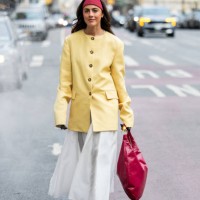Guest wears yellow jacket, red head band, bag, white skirt outside Altuzarra during New York Fashion Week on February 08, 2025 in New York City.