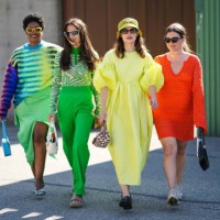 Guest wears yellow sunglasses, gold earrings, gold chain pendants necklaces, a black with multicolored print pattern wool pullover, a green ribbed...