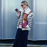 Guest wears YSL Saint Laurent sunglasses, a white ribbed wool striped black and white turtleneck pullover , a sleeveless brown leather aviator jacket...