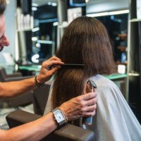 hairdresser holding clippers, cutting long hair for a bold new look at a modern salon. - hairstyle stock pictures, royalty-free photos & images