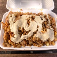 halal chicken and potato chips snack pack with tahini sauce in a cardboard takeout container on a wooden outdoor table - junk food stock pictures, royalty-free photos & images