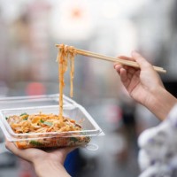 hand holding noodles with chopsticks on street - junk food stock pictures, royalty-free photos & images