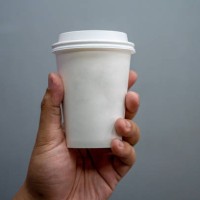 hand holds white disposable hot drink cup. - junk food stock pictures, royalty-free photos & images