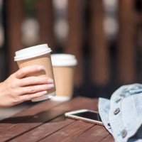 hand with a cup of coffee on a wooden background. a place for your ads. coffee day, coffee lovers. - junk food stock pictures, royalty-free photos & images
