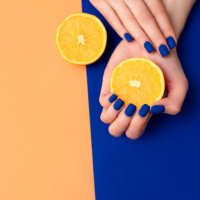 hand with artificial manicured nails colored with blue and orange nail polish on textile background - nails art stock pictures, royalty-free photos & images