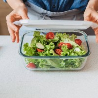 hands of a woman packing a healthy salad into a glass container to be taken away - food stock pictures, royalty-free photos & images