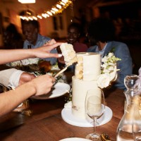 hands of newlywed couple cutting wedding cake near guests - home decoration stock-fotos und bilder
