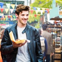 handsome british man walks through fair market with street food - food stock pictures, royalty-free photos & images
