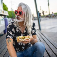 handsome hipster eating a big sandwich next to a food truck - junk food stock pictures, royalty-free photos & images