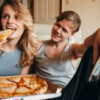 happiness couple eating a pizza at home - junk food stock pictures, royalty-free photos & images