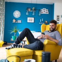 happy bearded man sitting on armchair and using smart phone - home decoration stock pictures, royalty-free photos & images