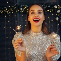 happy beautiful woman holding festive sparkler among christmas night - hairstyle stock pictures, royalty-free photos & images