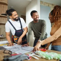 happy black couple and manual worker working on blueprints at home. - home decoration stock pictures, royalty-free photos & images