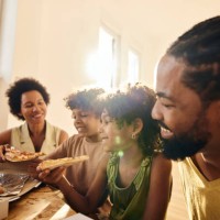 happy black family eating pizza in their new home. - junk food stock pictures, royalty-free photos & images