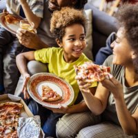 happy black mother and her daughter eating pizza at home. - junk food stock pictures, royalty-free photos & images