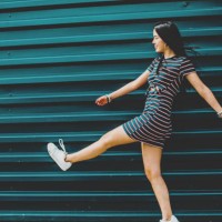 happy brunette young woman walking on street against blue wall - fashion stock pictures, royalty-free photos & images