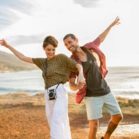 happy cheerful couple hand in hand at the coast at sunset - travel stock pictures, royalty-free photos & images