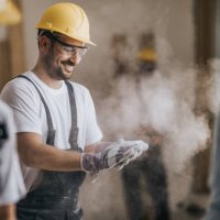 happy construction worker cleaning his gloves from sawdust at in renovating apartment. - home decoration stock pictures, royalty-free photos & images