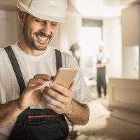 happy construction worker using cell phone during home renovation. - home decoration stock pictures, royalty-free photos & images
