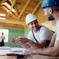 happy construction workers talking about plans while working in a house. - home decoration stockfoto's en -beelden